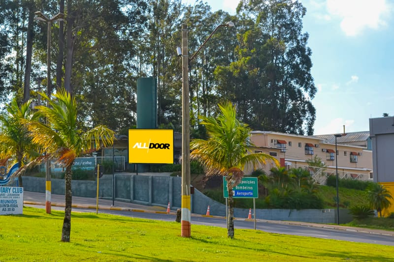 Painel de LED da AllDoor no acesso ao Open Mall, cercado por árvores